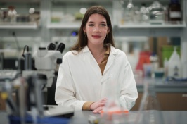 Woman in a white lab coat standing in a lab setting